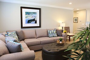 Ein Wohnzimmer mit einem beige-farbenen Sofa, einem Couchtisch und einem gerahmten Gemälde an der Wand.
