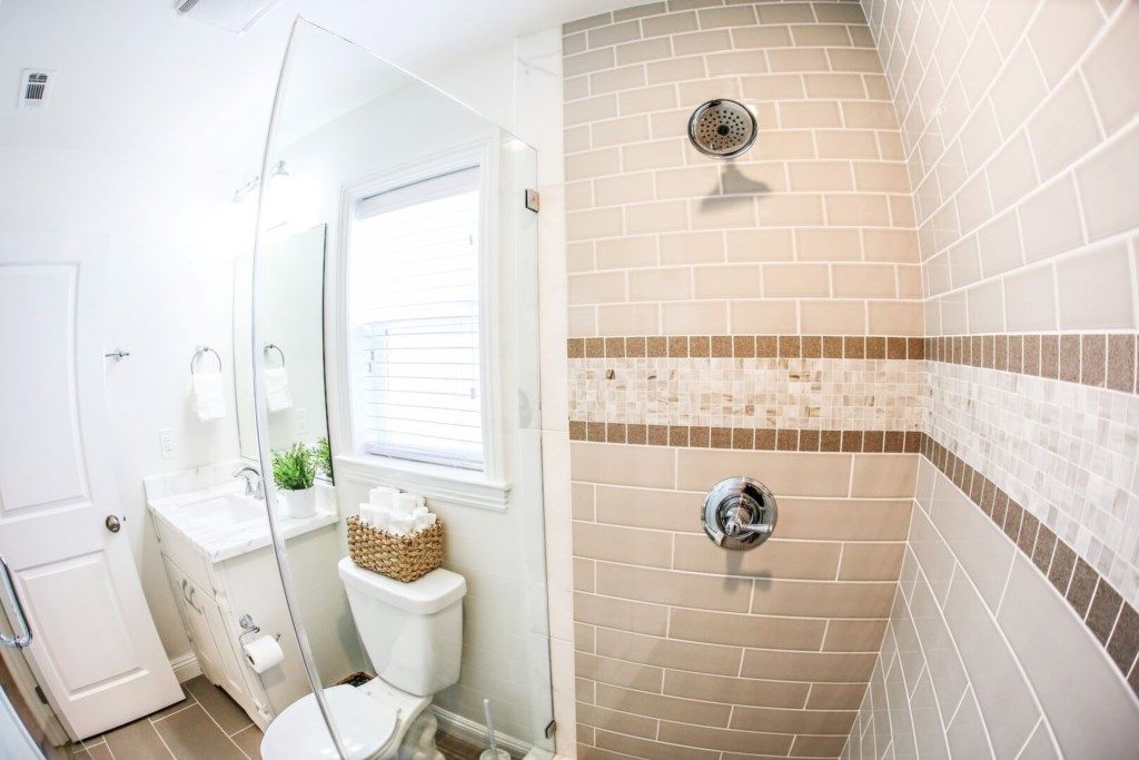 A bathroom with a shower, toilet, sink, and a glass-enclosed shower area.