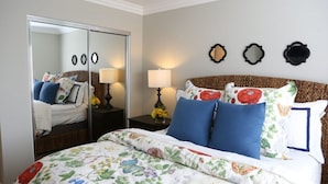 Een slaapkamer met een bed, een spiegel, een nachtkastje en een wand met drie decoratieve borden.