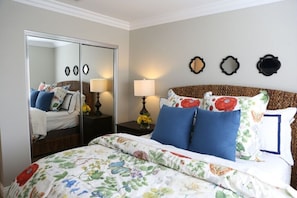 A bedroom with a bed, a mirror, a nightstand, and a wall with three decorative plates. - Adorable 3 Bedroom 2 Bath Home (Fullerton)