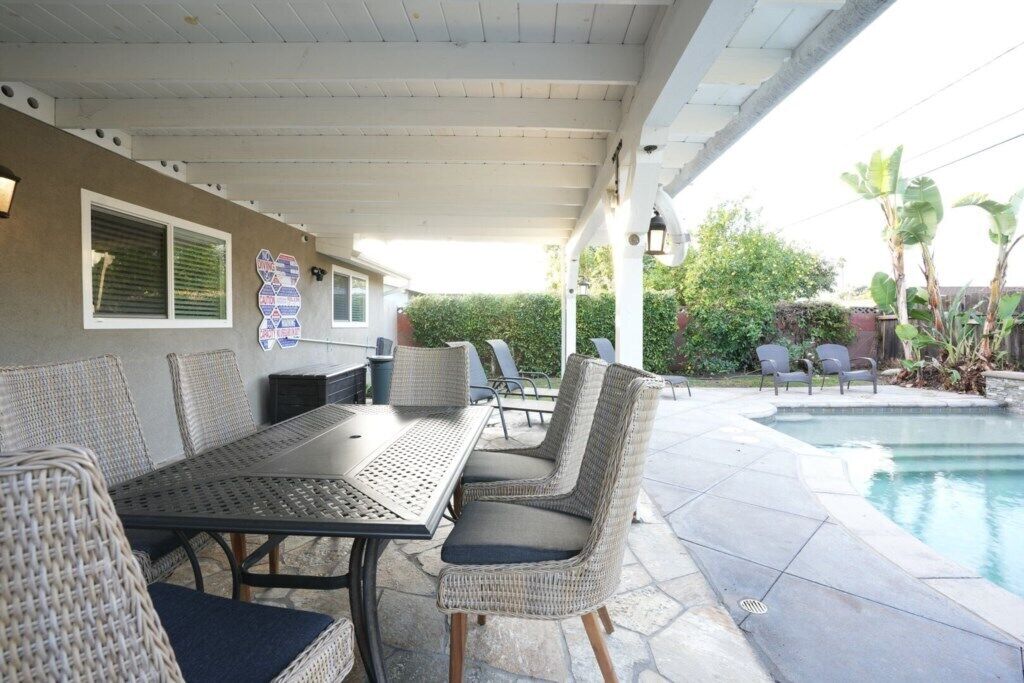An outdoor patio with a pool, wicker furniture, and a covered area with a ceiling.