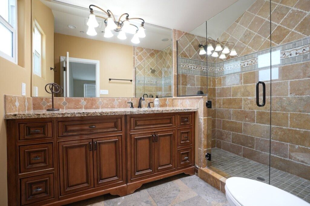 Une salle de bain dotée d’un grand meuble-lavabo, d’une douche à parois de verre et d’un miroir.