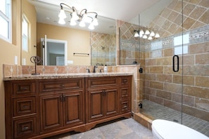 Un baño con un tocador amplio, cabina de ducha con mampara de vidrio y espejo.