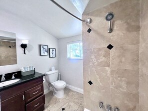 Une salle de bain comprenant des toilettes, un lavabo, un meuble-lavabo et une douche.