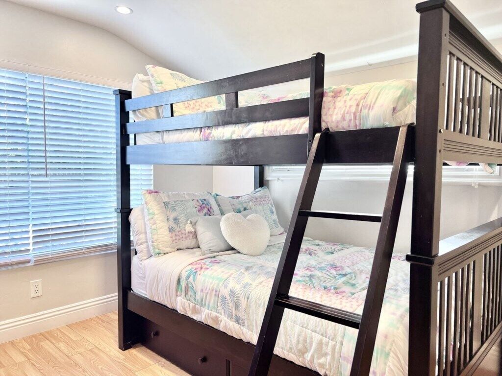 A bunk bed with a ladder, a floral bedspread, and a heart-shaped pillow.