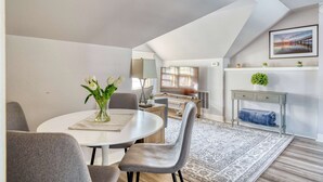 A dining area with a round table, grey chairs, and a vase of white flowers. - 2BR Upper unit - Sleeps 4 - Trendy Area - Walk Everywhere (Portland)