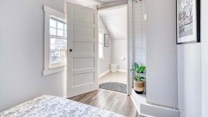 A bedroom with a bed, a door leading to a hallway, a window, and a framed picture on the wall. - 2BR Upper unit - Sleeps 4 - Trendy Area - Walk Everywhere (Portland)