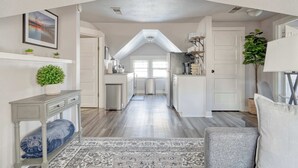 A spacious hallway with a high ceiling, a built-in bench, a patterned rug, and a view into a kitchen area. - 2BR Upper unit - Sleeps 4 - Trendy Area - Walk Everywhere (Portland)