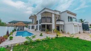 Una casa moderna de dos pisos con piscina, un porche cubierto y un jardín bien cuidado.