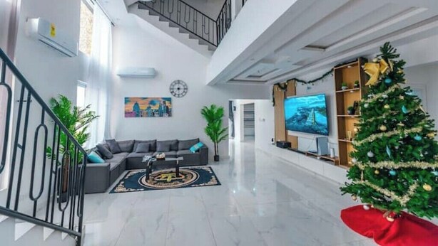 Amplia sala de estar con una escalera moderna, un televisor de pantalla plana y un árbol de Navidad.