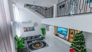 Amplia sala de estar con una escalera, un televisor, un árbol de Navidad y un sofá.
