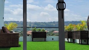 Terraza en la azotea con césped artificial, una zona de estar y vistas a un paisaje montañoso.
