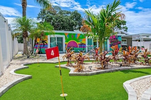 Une fresque murale aux couleurs vives, un drapeau portant le chiffre « 4 », et des plantes tropicales.