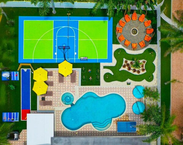 Un terrain de sport, des sièges en plein air, une piscine et un espace de jeux pour enfants.