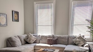 A living room with a sectional sofa, a coffee table, and a ceiling fan. - Mellow ☮ BnB, a NEW 3/1.5 in Victorian District (Savannah)