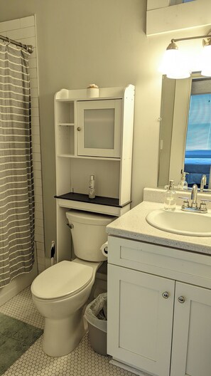 A bathroom with a toilet, sink, and mirror.