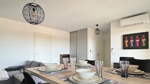 A modern dining area with a wooden table set for four, black chairs, and a large mirror on the wall.