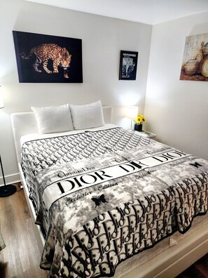 A hotel room with a bed, a nightstand with a lamp and flowers, and artwork on the walls.