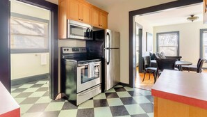 A kitchen with a microwave, oven, and refrigerator, wooden cabinets, and a checkered floor. - 2BR - Sleeps 6 - Perfect Location for Foodies (Portland)