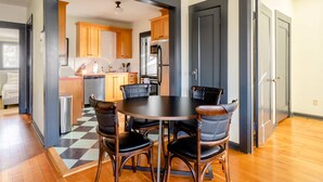 A modern kitchen with wooden cabinets, a stainless steel refrigerator, and a black dining table with four chairs. - 2BR - Sleeps 6 - Perfect Location for Foodies (Portland)