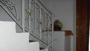 A staircase with white railings and a small table with a basket of flowers. - Friendly Hostel (Gjirokaster)