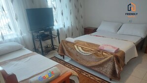 A room with two beds, a TV on a stand, and a Google towel on one bed. - Friendly Hostel (Gjirokaster)