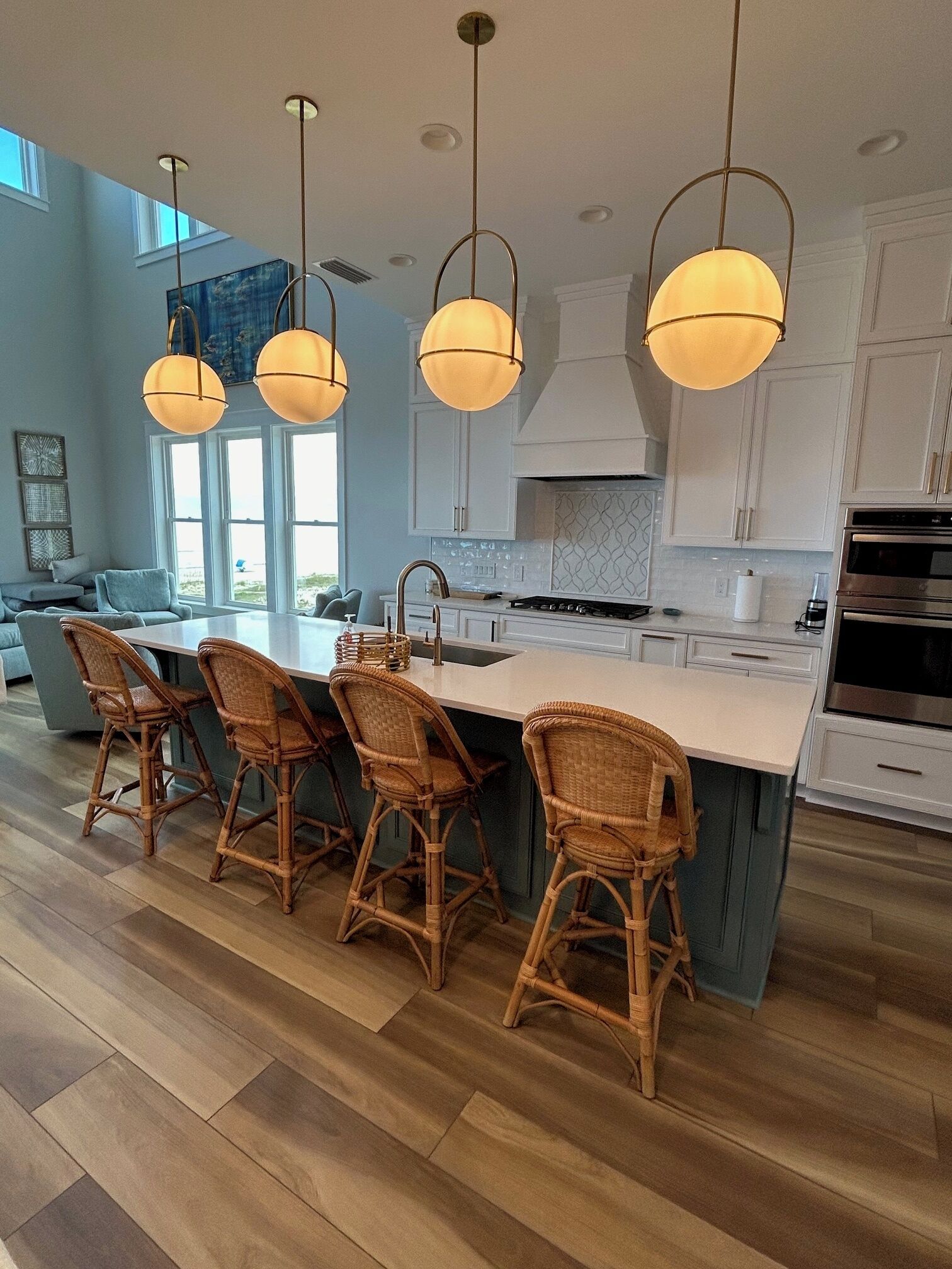 A modern kitchen with a central island, white cabinetry, and a dining area with wicker chairs.