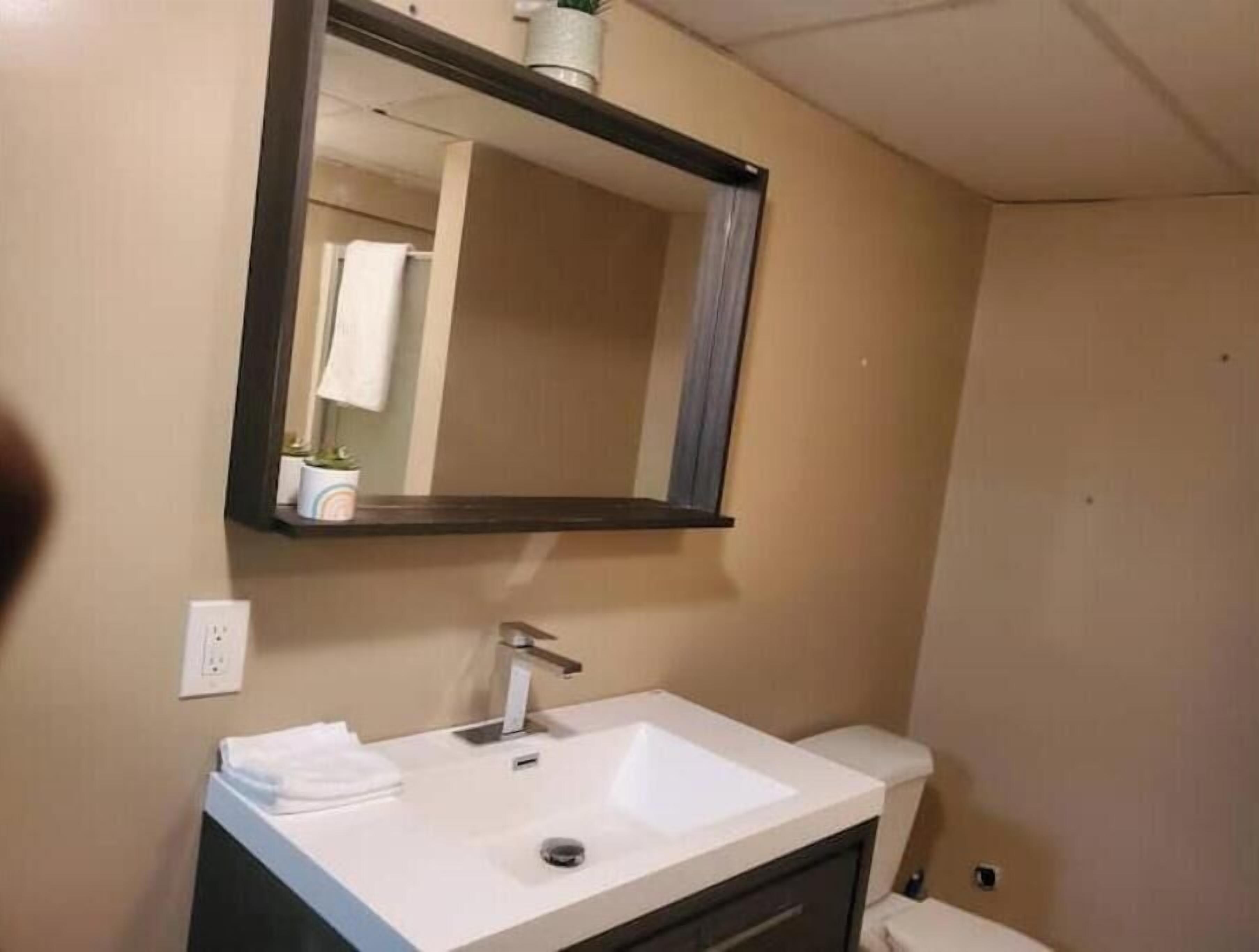 Un baño con lavamanos blanco, espejo y toalla.