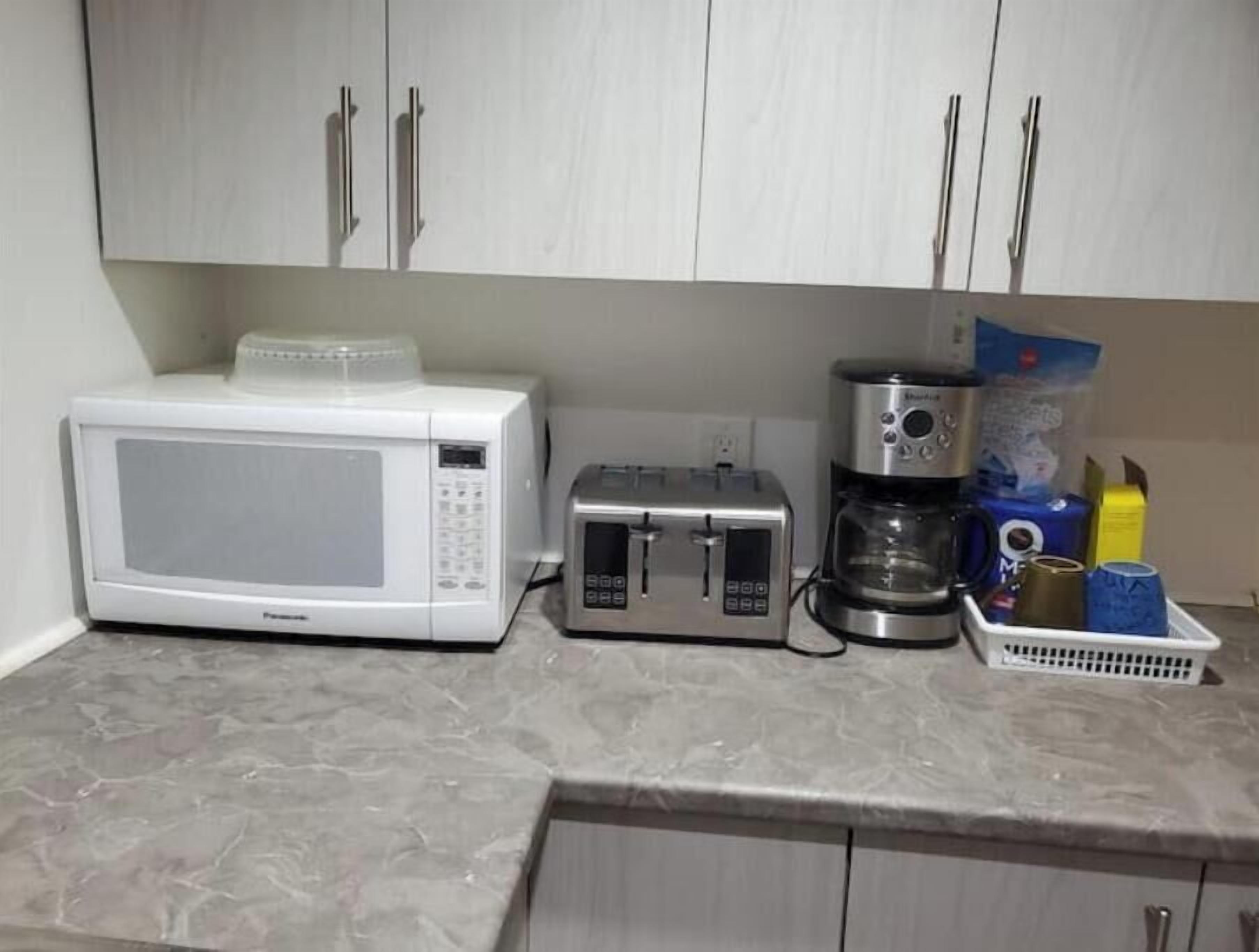 Una cocina con microondas, tostadora y cafetera en la encimera.