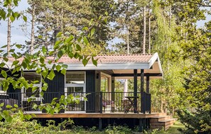 A modern cabin with a wooden deck, large windows, and a covered outdoor seating area surrounded by trees. - 4 bedroom stunning home in Rørvig (Rørvig)