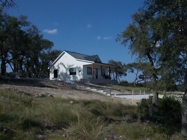 A single-story house with a sloped roof, a front porch, and a small front yard. - Spring Branch Cottages "Mountain Laurel" (Comal County)