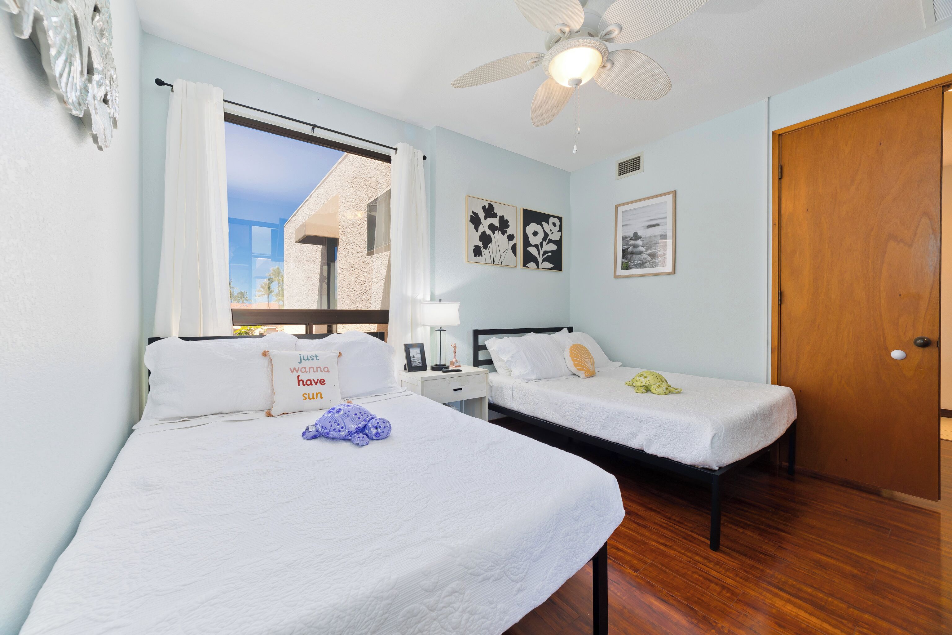 A bedroom with two single beds, a ceiling fan, and a window with curtains.