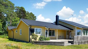 A yellow building with a black roof, a chimney, and a porch with steps leading to a door.