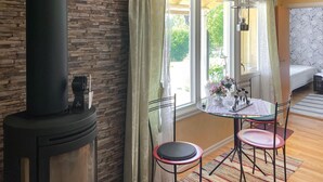 A cozy room with a stone wall, a glass table with chairs, a window with curtains, and a bed with floral wallpaper.
