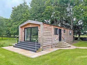 A log cabin with a glass door entrance, a small porch, and a stone staircase leading to the door. - 2 bedroom accommodation in Ingleton (Ingleton)