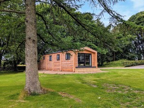A small wooden cabin with a porch, surrounded by lush greenery and trees. - 2 bedroom accommodation in Ingleton (Ingleton)