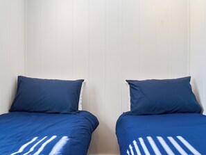 Two single beds with dark blue bedding and white pillows against a white wall. - 2 bedroom accommodation in Ingleton (Ingleton)