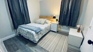 Un dormitorio con cama, mesita de noche, lámpara y una pequeña mesa con un florero.