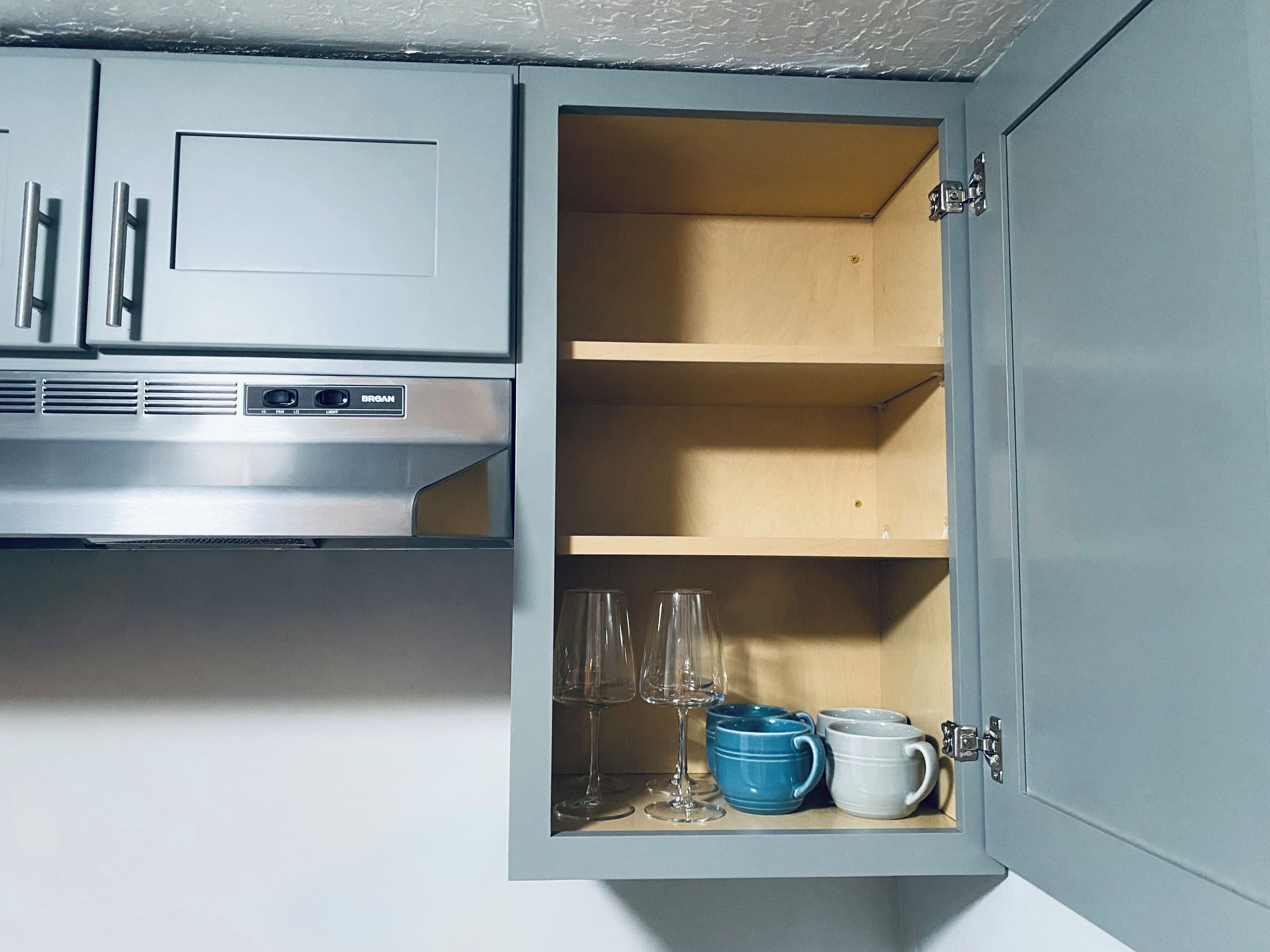 Eine Küche mit Einbau-Mikrowelle und einem Schrank, der ein Weinglas und zwei Tassen enthält.