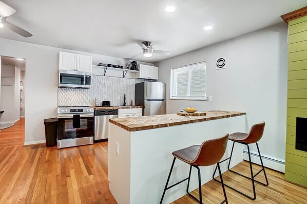 A modern kitchen with a central island, stainless steel appliances, and a ceiling fan.