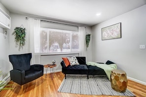 A modern living room with a black sofa, a black armchair, a patterned rug, and a hexagonal side table.