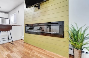 A kitchen with a built-in microwave, a bar stool, and a potted plant.
