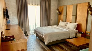 A hotel room with a large bed, wooden furniture, a desk, and a view of the outdoors. - Hotel Atlantis Mazagan (Moulay Abdallah)