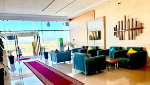 A spacious lobby with a red carpet, multiple seating areas, and a large wall-mounted TV. - Hotel Atlantis Mazagan (Moulay Abdallah)