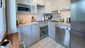 Una cocina moderna con armarios blancos, microondas, cafetera y lavavajillas.