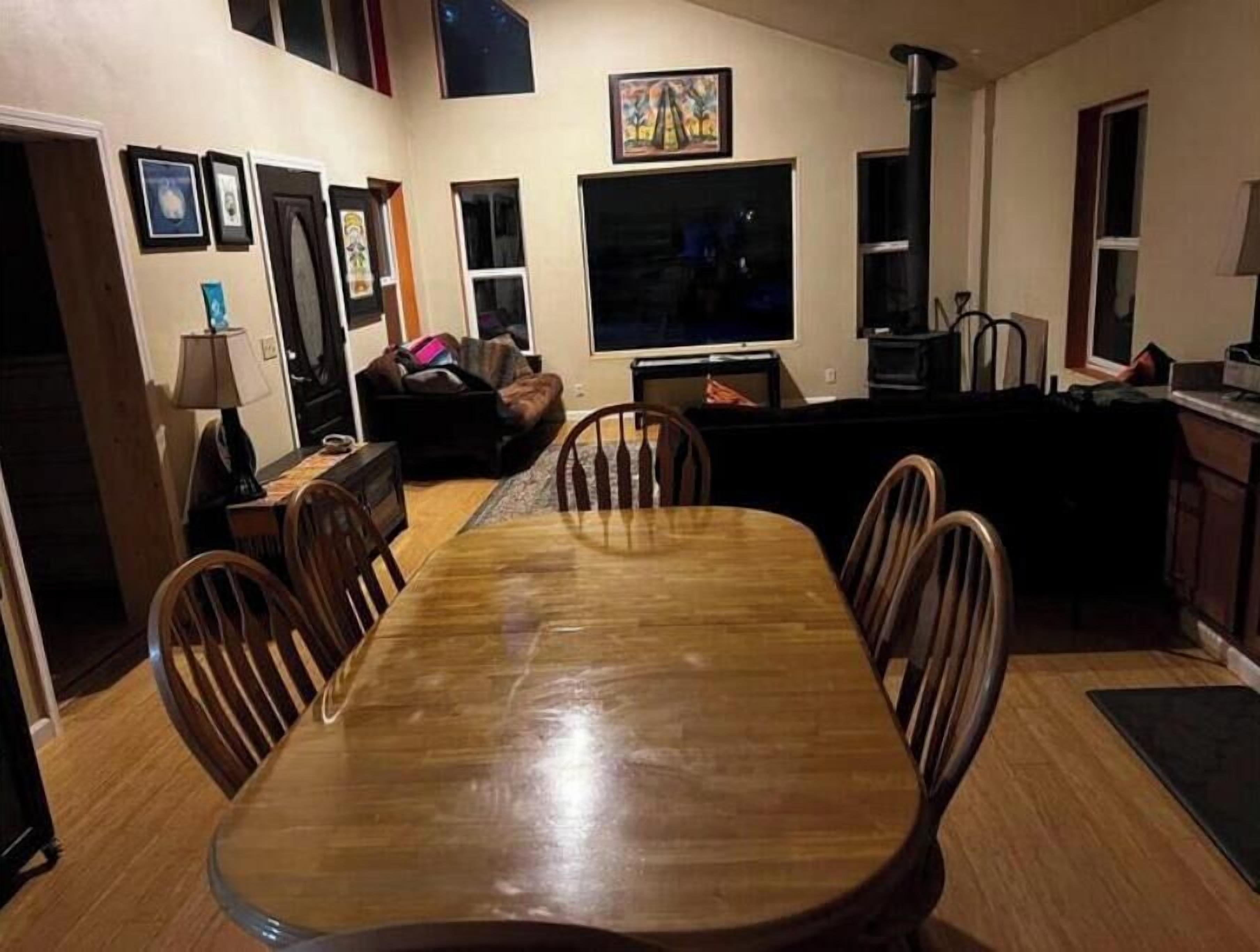 A dining area with a wooden table and chairs, a sofa, a TV, and a fireplace.