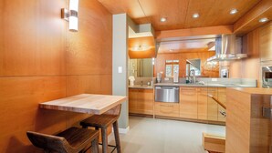 Una cocina moderna con armarios de madera, un lavavajillas de acero inoxidable y una mesa de comedor de madera con dos taburetes.