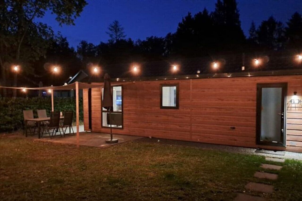 Una cabaña de madera con un patio, un comedor y una pequeña cocina exterior.