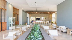 A modern hotel lobby with a central planter, seating areas, and a reception desk. - The Beach is Your Backyard! Ocean front, mountain views, and amazing sunset! (Santa Marta)