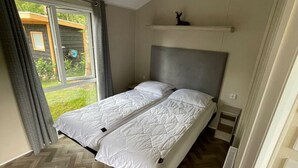 Ett sovrum med en säng, ett fönster och utsikt över grönområden utanför.